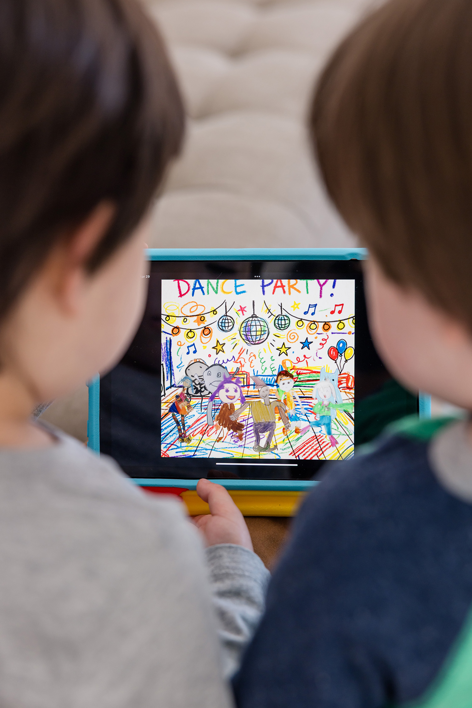 Two kids watching an animated DANCE PARTY drawing on a tablet